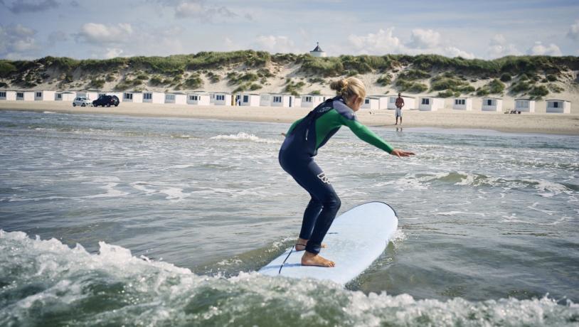 Jente som surfer på Løkken strand