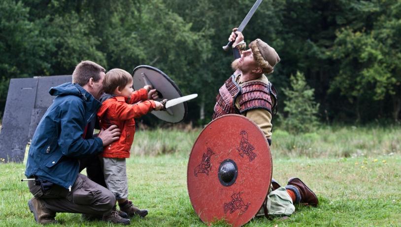 Far og barn leker med viking ved Ribe Vikingecenter