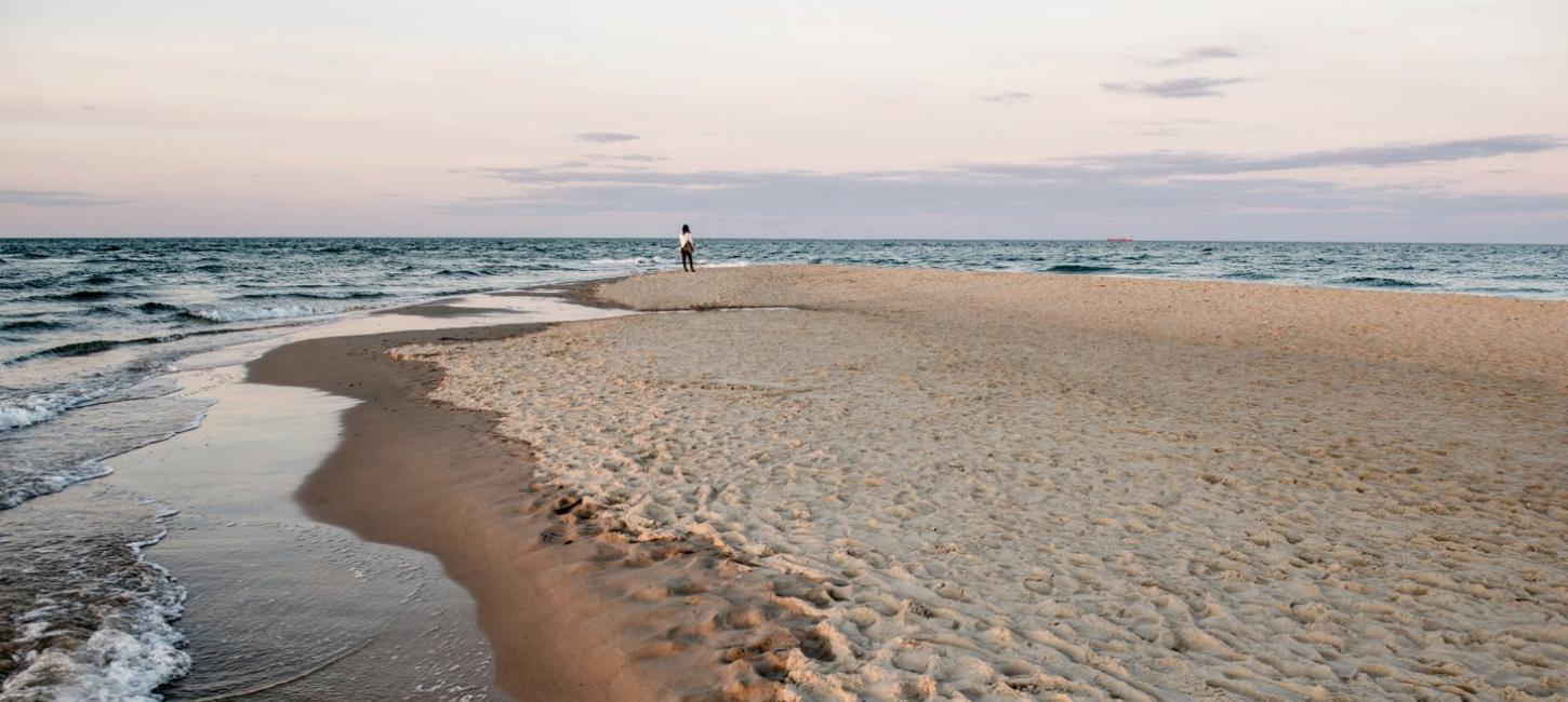 Kvinne som står på stranden på Grenen i Skagen i Danmark