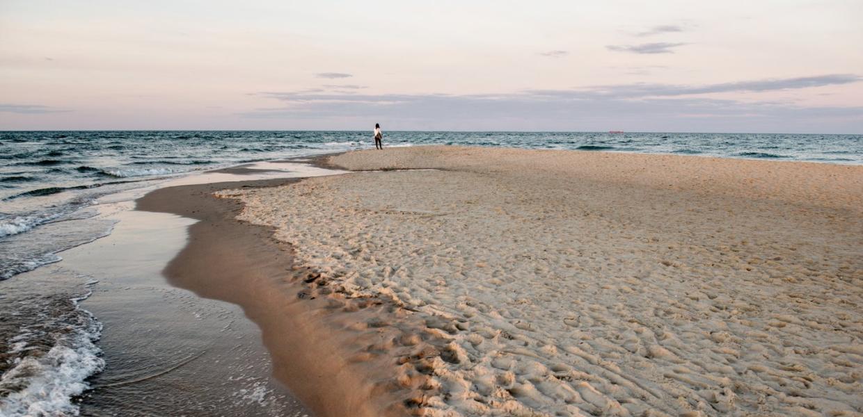 Kvinne som står på stranden på Grenen i Skagen i Danmark