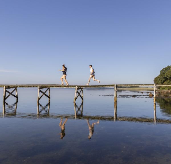 Een stel rent over de brug naar zee bij Sondrup Strand aan het Horsens Fjord