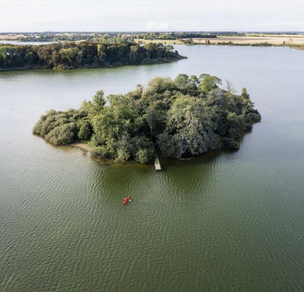 Een kajakker vaart naar een oonbewoond eiland van natuurpark Maribo Lakes