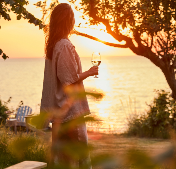 Kvinne med vinglass i solnedgang ved Helenekilde badehotel