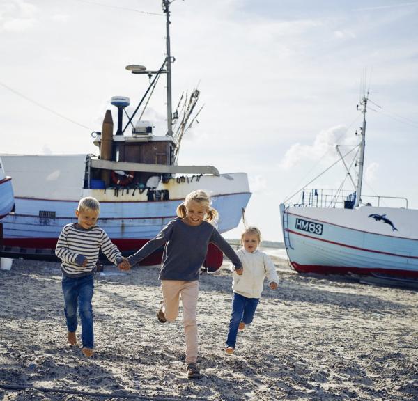 Tre barn som løper på Thorup strand i Nordjylland