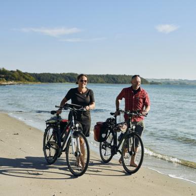 People walking on beach with their bikes on Djursland, East Jutland