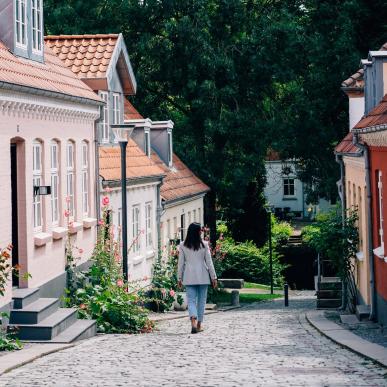 kvinne som går nedover brosteinsgate i Odense 