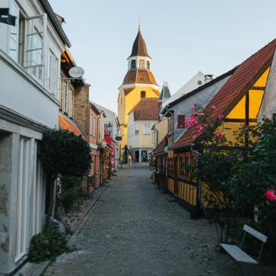 Brosteinsgate med fargerike hus, stokkroser og roser i Faaborg