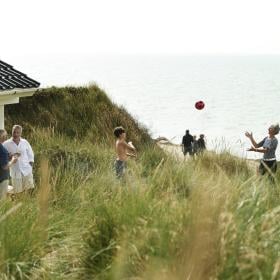 Familie som leker ved feriehuset i Jylland