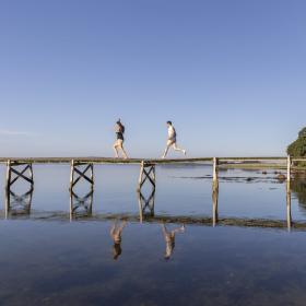 Een stel rent over de brug naar zee bij Sondrup Strand aan het Horsens Fjord